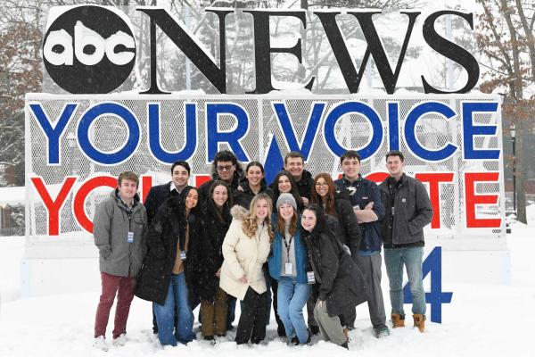 Student ambassadors standing in front of ABC's debate logo on campus