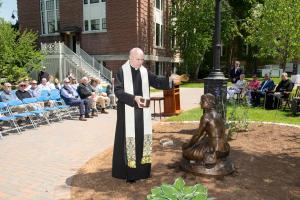 A member of the monastic community blesses the Joan of Arc statue