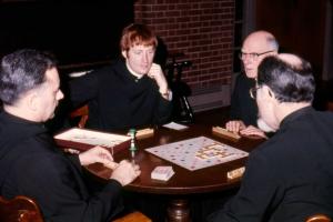 Archival photo of Abbot Mark Cooper playing a board game with fellow monks