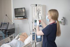 Nurse standing in front of an IV bag and manikin