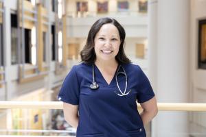 Nurse stands in navy blue scrubs with a stethoscope