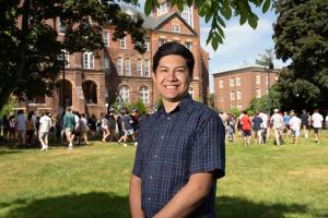 Roque Otazo standing on Alumni Quad with students in the background