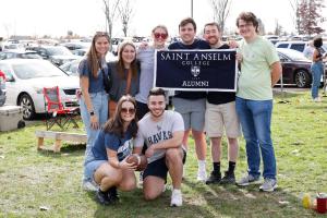 Students posing with a Saint Anselm Banner at Homecoming 2022