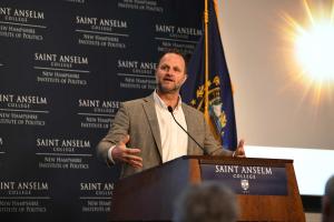 Max Latona speaking behind a podium at an event