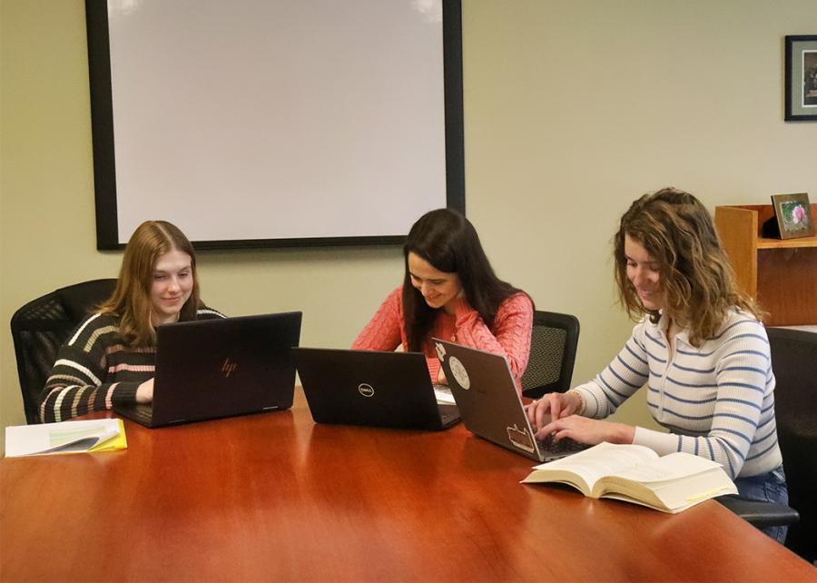 Students work on their laptop at a table