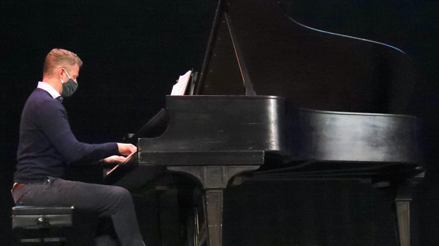 A Saint Anselm professor playing piano on stage.