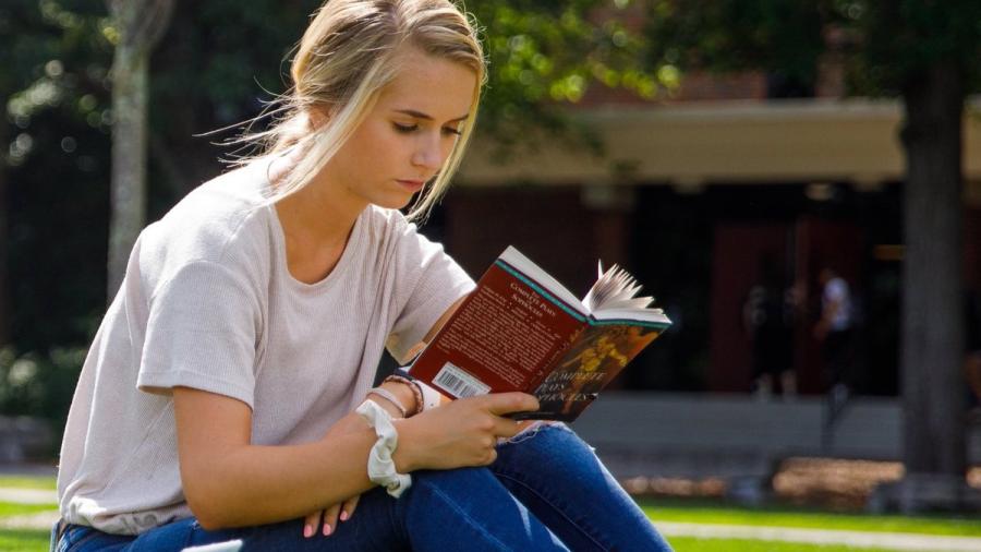 A student reading a book outdoors