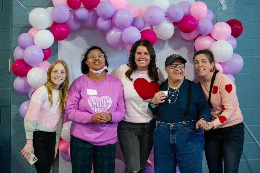 Students under pink and purple balloons at the Valentines dance