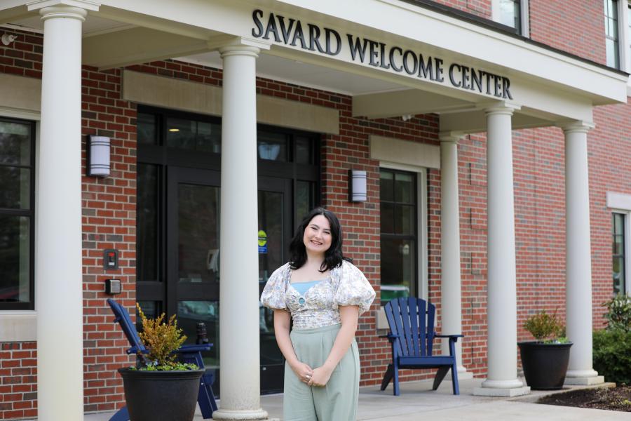 Jill Dorazio '24 standing and smiling in front of the Savard Welcome Center