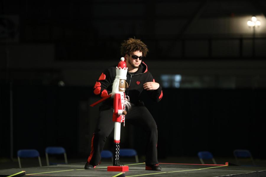 Student participant in the fashion show standing in an outfit alongside a nutcracker